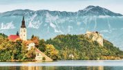 Lake Bled located in Slovenia Europe. There is a Church on the Island and ancient castle on top of a rock. Beautiful blue sky with dramatic cloudscape over the reflection in the Bled Lake. Story in such a beautiful sunny day on sunset. European Alps in the background.